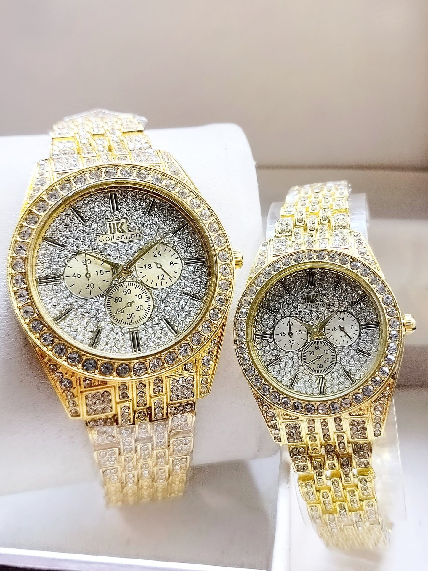 Two gold watches with diamond-studded faces on a white surface.
